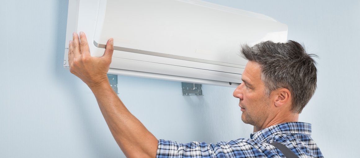Portrait Of A Mid-adult Male Technician Fixing Air Conditioner On Wall